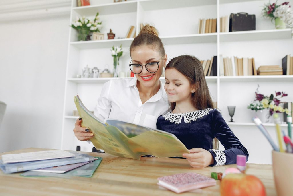 Eine Frau und ein Mädchen genießen ein Buch in gemütlicher häuslicher Atmosphäre und fördern so Bildung und familiären Zusammenhalt.
