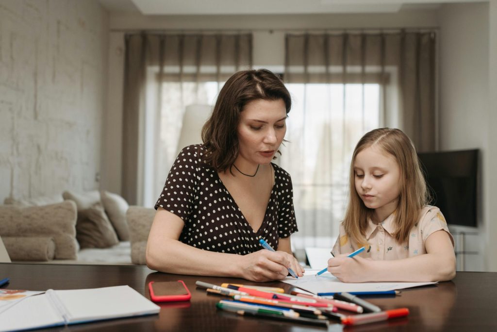 Eine Mutter und ihre Tochter sitzen zusammen zu Hause, zeichnen und verbringen Zeit miteinander.
